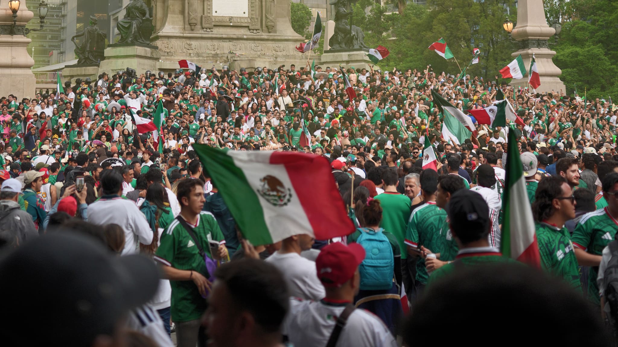 Una multitud inmensa celebrando bajo el Ángel de la Independencia, gente de verde, banderas en alto.