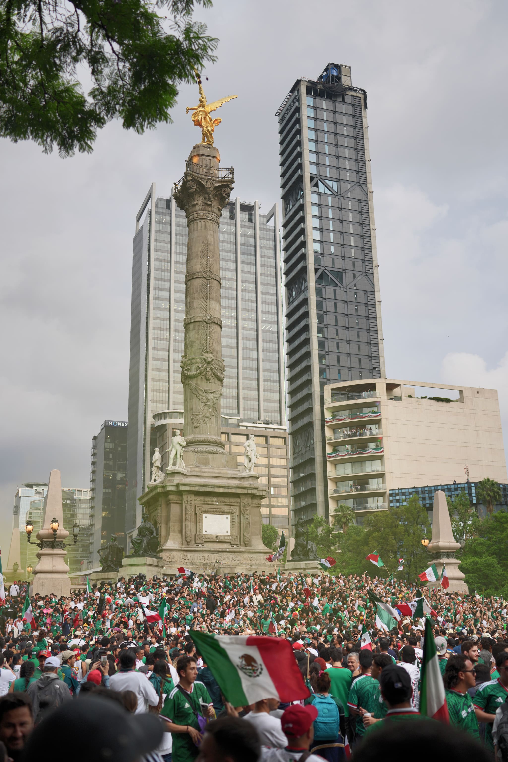 Una multitud inmensa celebrando bajo el Ángel de la Independencia, gente de verde, banderas en alto.